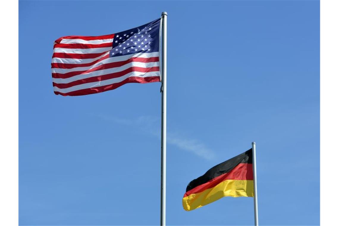 Die US-amerikanische und die deutsche Nationalflagge wehen vor dem Haupttor des US-Militärflughafens. Foto: Harald Tittel/dpa