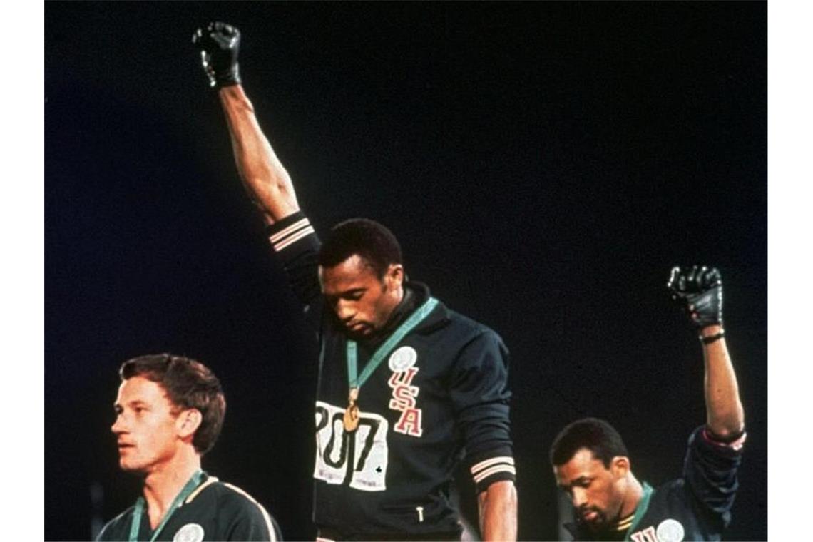 Die US-Athleten Tommie Smith (M) und John Carlos (r) streckten während Olympia 1968 die Fäuste, um gegen Rassismus zu protestieren. Foto: Anonymous/AP/dpa