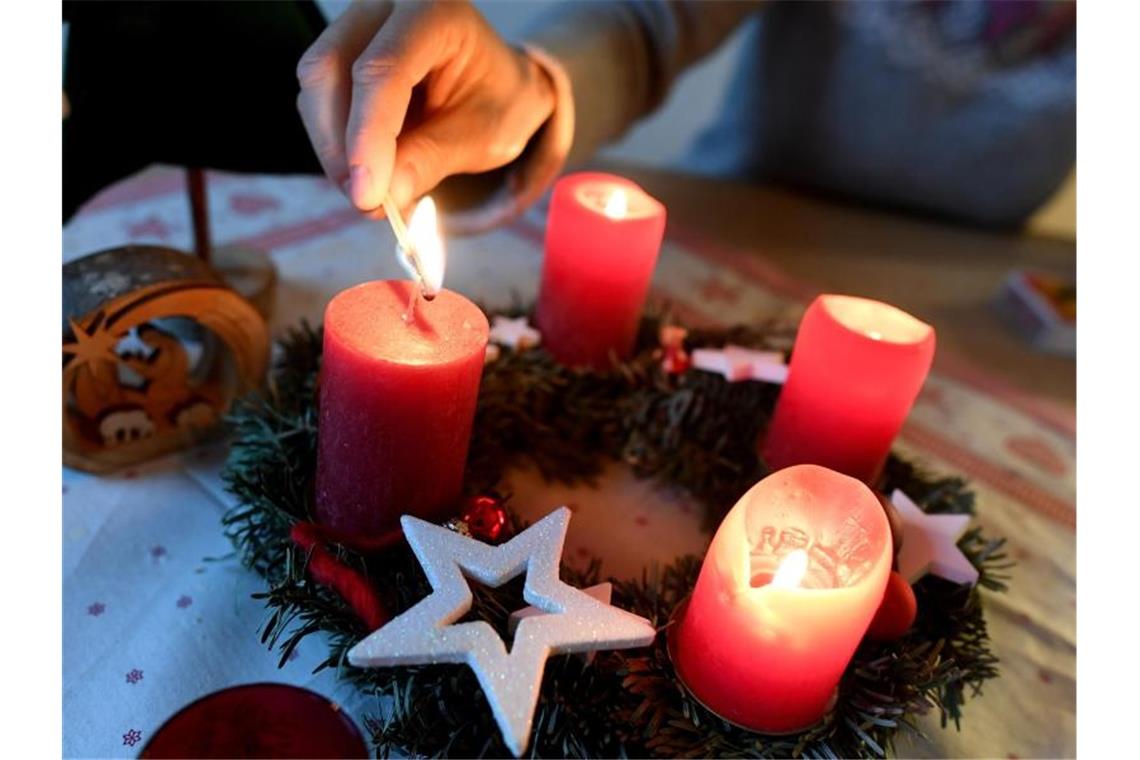 Die vier Kerzen eines Adventskranzes leuchten. Foto: Angelika Warmuth/dpa/Archivbild