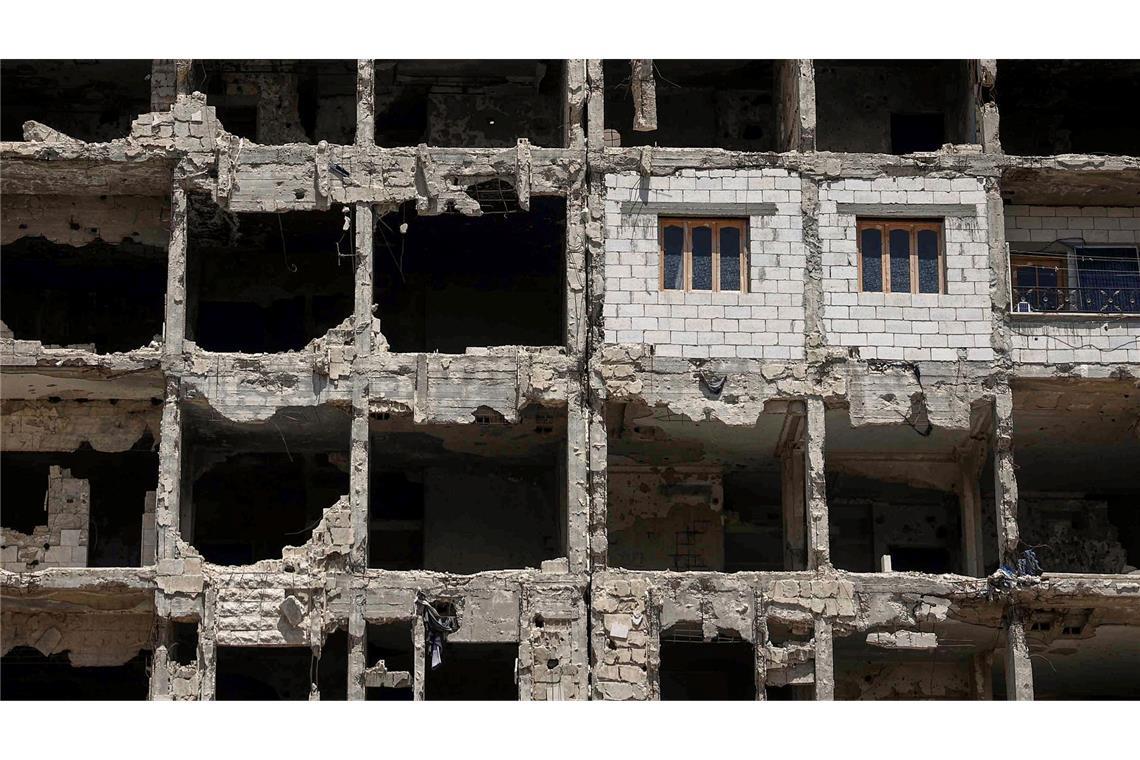Bilder des Tages Die Wände und Fenster einer kürzlich restaurierten Wohnung ragen aus einem beschädigten Wohnhaus im vom Krieg zerstörten Viertel Al-Waer heraus.