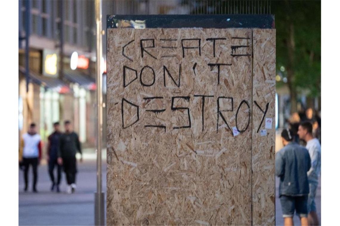 Entsetzen nach Stuttgarter Chaos-Nacht Die Worte „Create don't Destroy“ (Erschaffe statt zu zerstören) stehen auf Holzplatten, mit denen in Stuttgart die beschädigte Scheibe einer Werbetafel abgedeckt worden ist. Foto: Marijan Murat/dpa