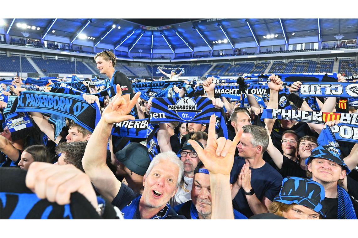 Die Zuschauer im Stadion feiern und halten Schals in die Höhe.