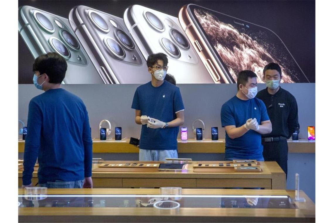 Dieser Apple-Store in Peking hat zwar wieder geöffnet, die Mitarbeiter schützen sich aber trotzdem weiter mit Mundschutz und Handschuhen. Foto: Mark Schiefelbein/AP/dpa