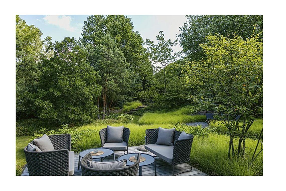 Dieser Garten wird von Grün dominiert. Er ist unaufdringlich. Die Terrasse liegt auf der Waldlichtung.