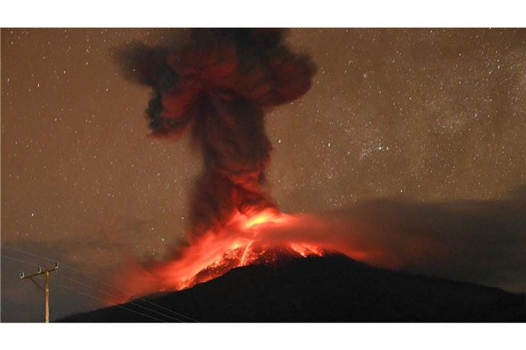 Dieses Bild zeigt den Kegel am Vulkan Lewotobi Laki-Laki. Bei dem Ausbruch steigt eine hohe Aschewolke in den Himmel und glühende Lava rinnt die Hänge hinunter.