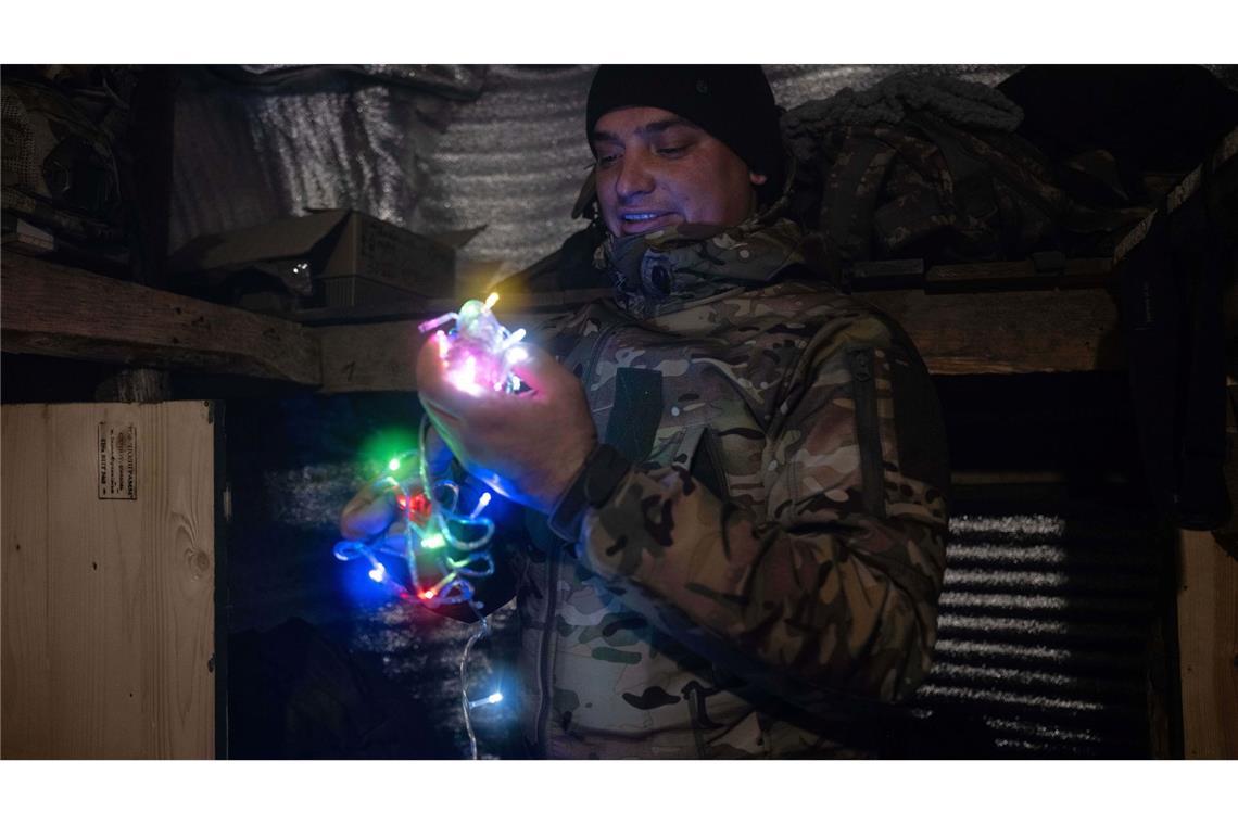 Dieses vom Pressedienst der 93. mechanisierten Brigade der Ukraine zur Verfügung gestellte Foto zeigt einen Soldaten an der Frontlinie in der Nähe von Kostjantyniwka in der Region Donezk, der eine Neujahrsgirlande hält.