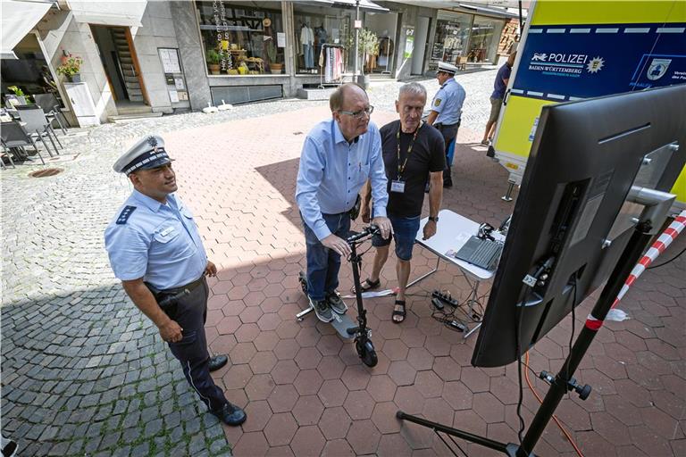 Dieter Knecht testet unter den wachsamen Augen von Polizist Vedat Boy (links) und Guido Greiner seine Reaktionszeit bei unterschiedlichen Gefahrenszenarien auf dem Simulator. Foto: Alexander Becher