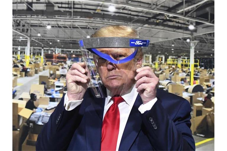 Donald Trump hält während des Rundgangs in einem Ford-Werk ein Gesichtsvisier in den Händen - einen Mundschutz trug er trotz Aufforderung nicht. Foto: Daniel Mears/Detroit News/AP/dpa