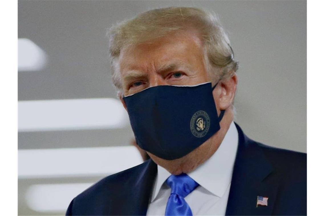 Nach schlechten Umfragewerten: Trump wirbt für Mundschutz Donald Trump mit einem Stoff-Mundschutz, auf dem das Präsidenten-Siegel abgebildet ist. Foto: Patrick Semansky/AP/dpa