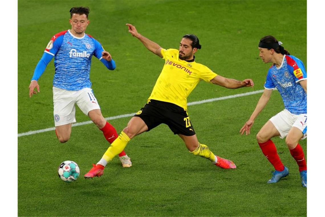 Dortmunds Emre Can (M) kommt vor Kiels Fabian Reese (l) an den Ball. Foto: Friedemann Vogel/epa Pool/dpa