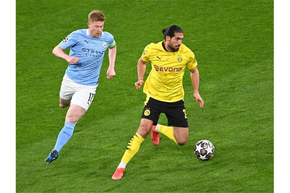 Dortmunds Emre Can (r) kann sich am Ball gegen Kevin De Bruyne behaupten. Foto: Federico Gambarini/dpa-Pool/dpa