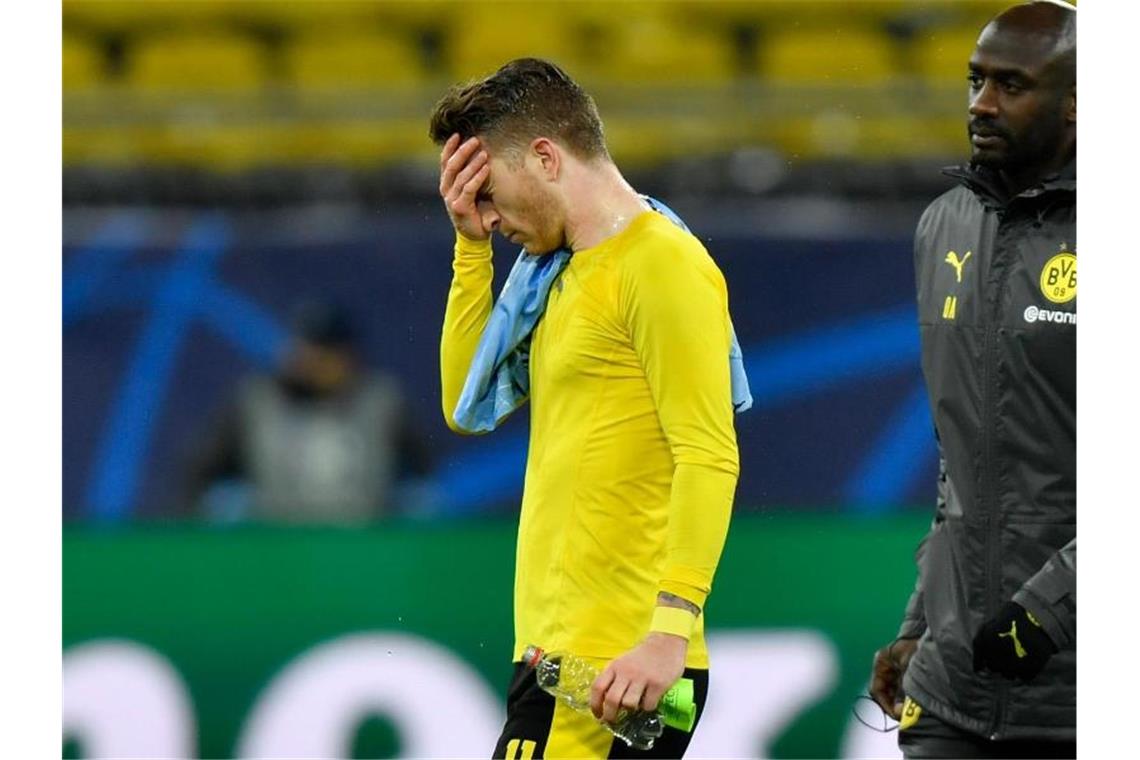 Dortmunds Kapitän Marco Reus (l) verlässt traurig den Platz. Der Traum vom Halbfinale ist geplatzt. Foto: Martin Meissner/AP-Pool/dpa