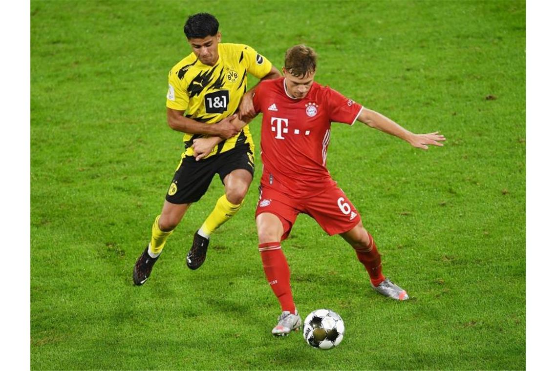 Dortmunds Mahmoud Dahoud (l) versucht Bayerns Joshua Kimmich den Ball abzunehmen. Foto: Andreas Gebert/Reuters/Pool/dpa