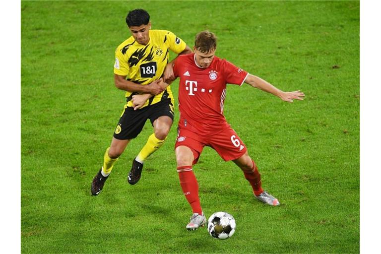 Dortmunds Mahmoud Dahoud (l) versucht Bayerns Joshua Kimmich den Ball abzunehmen. Foto: Andreas Gebert/Reuters/Pool/dpa