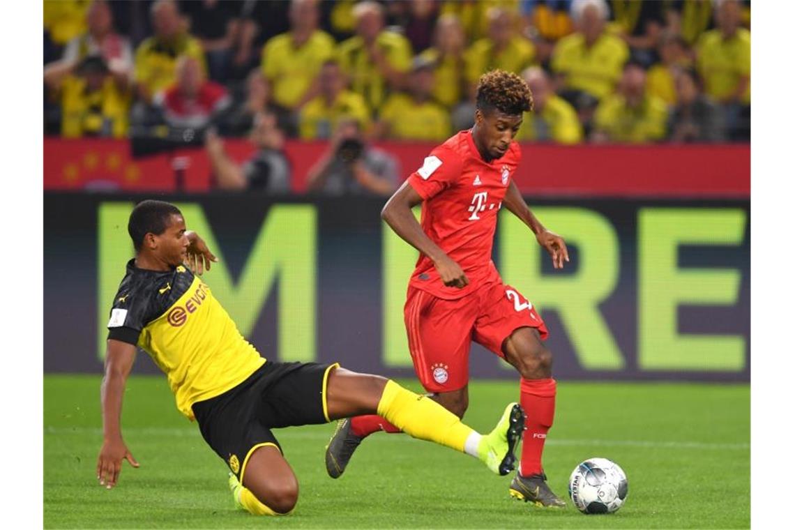 Dortmunds Manuel Akanji (l) und Bayerns Kingsley Coman kämpfen um den Ball. Foto: Marius Becker