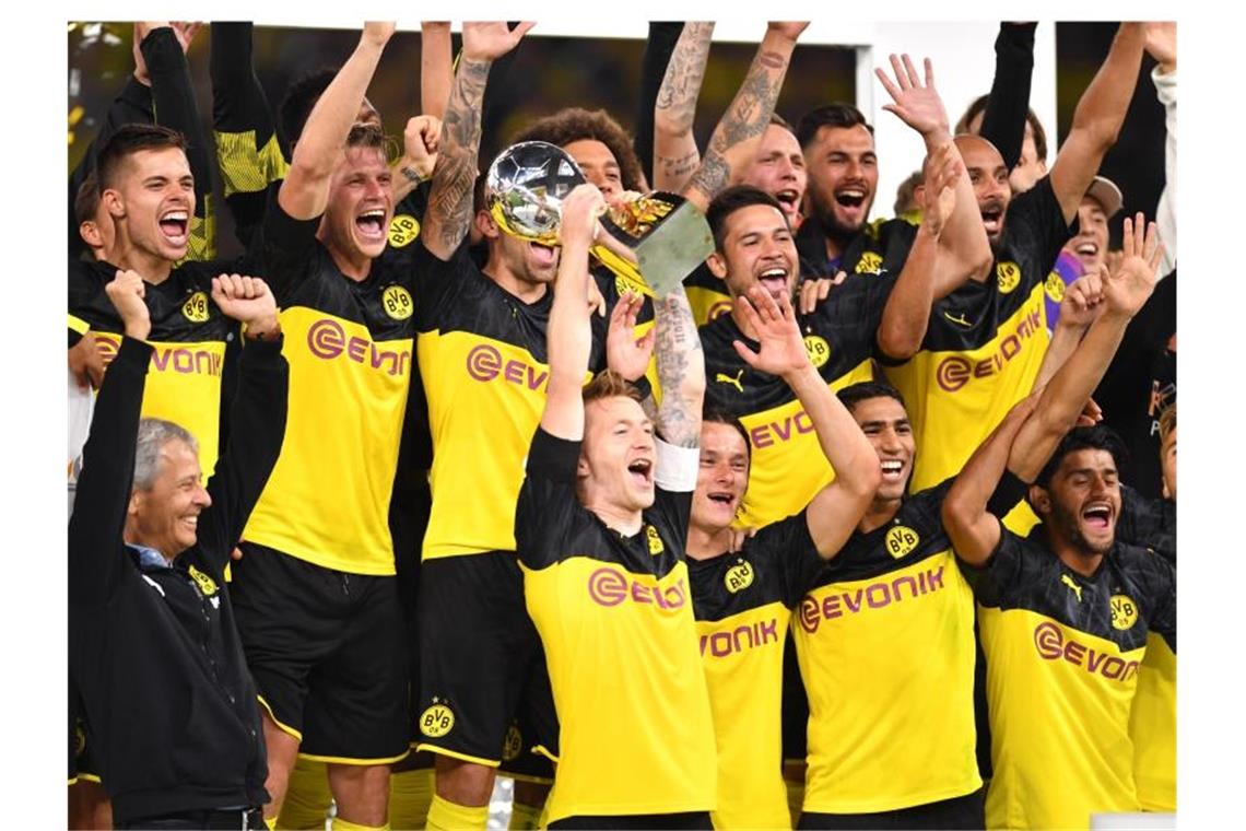 Dortmunds Marco Reus (M) bejubelt mit seinem Trainer Lucien Favre (l) und Mitspielern den Gewinn des Supercups 2019. Foto: Marius Becker