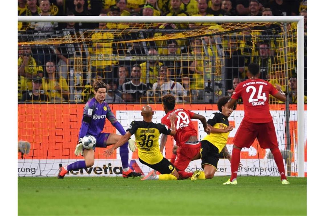 Dortmunds Torhüter Marwin Hitz (l) pariert glänzend einen Schuss von Bayerns Kingsley Coman (M). Foto: Marius Becker