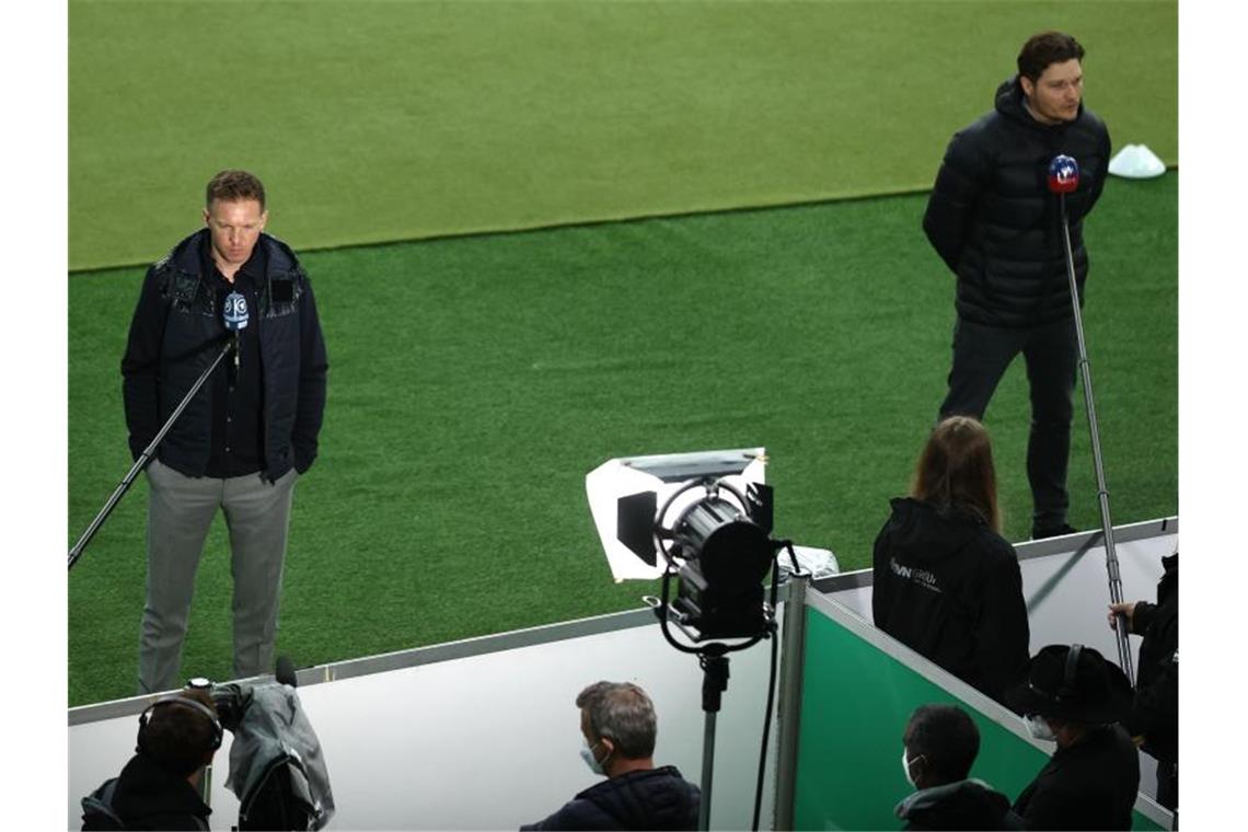 Dortmunds Trainer Edin Terzic (r) und Leipzigs Trainer Julian Nagelsmann geben vor dem Anpfiff des DFB-Pokalfinals TV-Interviews. Foto: Maja Hitij/Getty-Pool/dpa