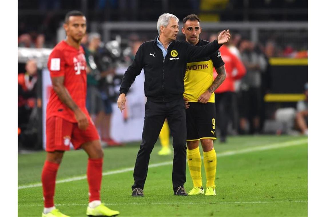 Dortmunds Trainer Lucien Favre (M) gibt Stürmer Paco Alcacer Anweisungen. Links steht Bayerns Thiago. Foto: Marius Becker