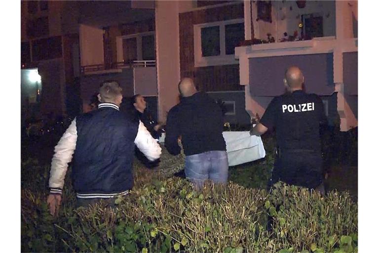 Dramatische Szenen in Rostock: Polizisten und Anwohner stehen vor einem Hochhaus und breiten ein Tuch aus, als ein Mann in einem Obergeschoss einen Säugling über die Balkonbrüstung hält und droht, ihn fallen zu lassen. Foto: Stefan Tretropp