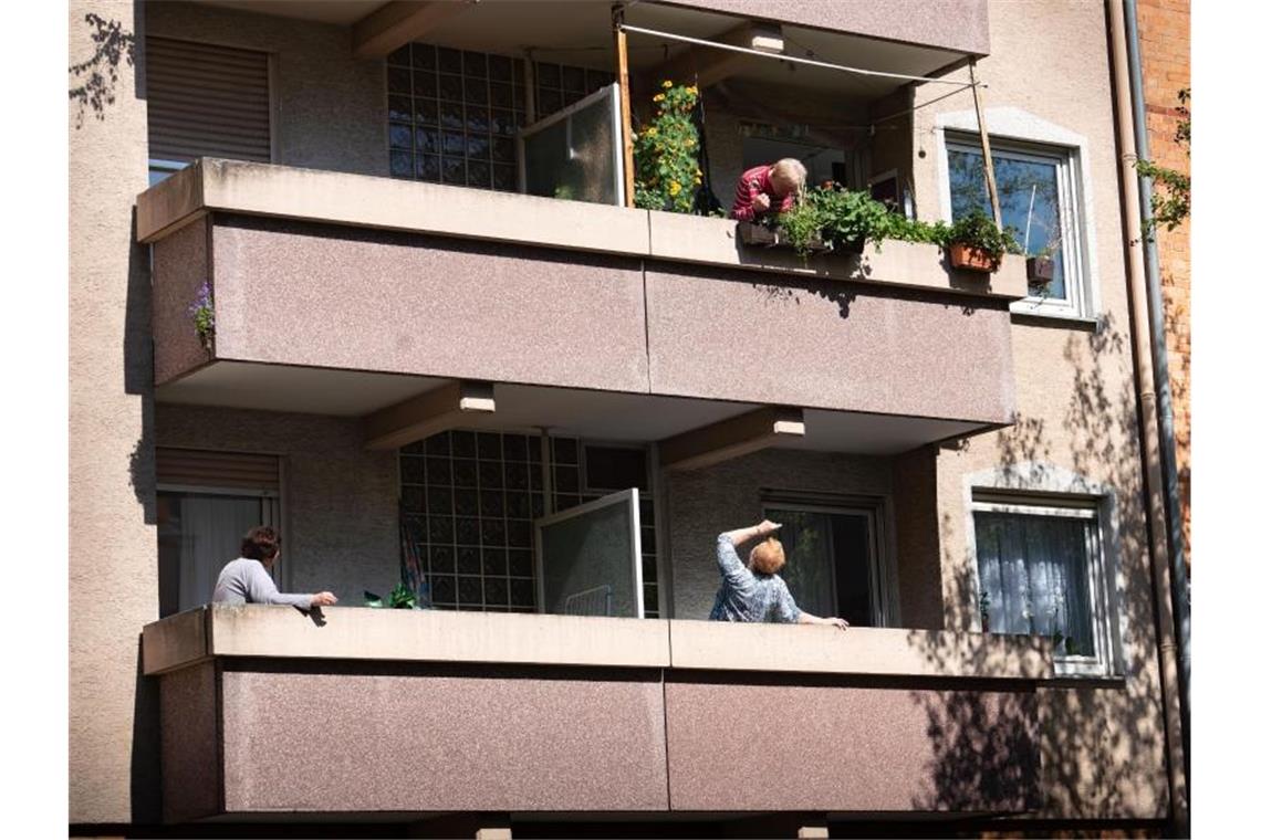 Drei ältere Menschen stehen jeweils auf ihren eigenen Balkonen und unterhalten sich. Foto: Frank Rumpenhorst/dpa