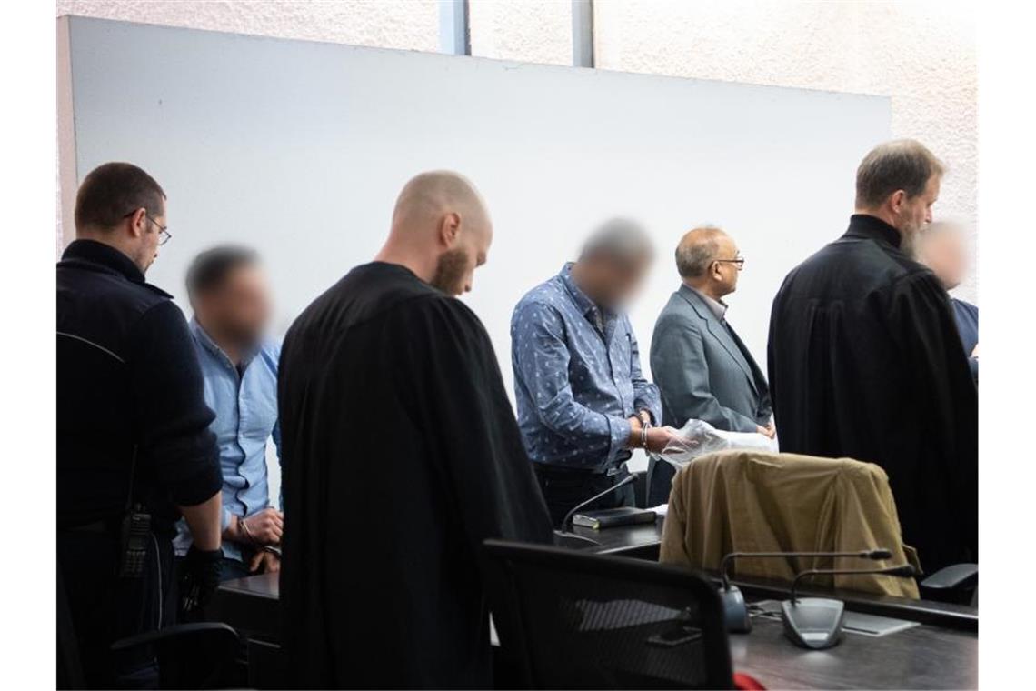 Drei Angeklagte vor Urteilsverkündung im Prozess um millionenschwere Geldwäsche neben ihren Anwälten. Foto: Sebastian Gollnow/dpa