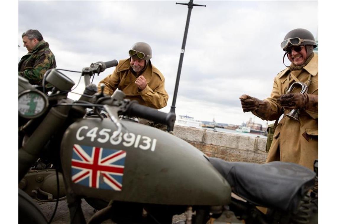 Staats- und Regierungschefs gedenken D-Day in Portsmouth Drei Briten stehen in historischen Uniformen mit historischen Motorrädern in der Altstadt von Portsmouth. Foto: Kay Nietfeld