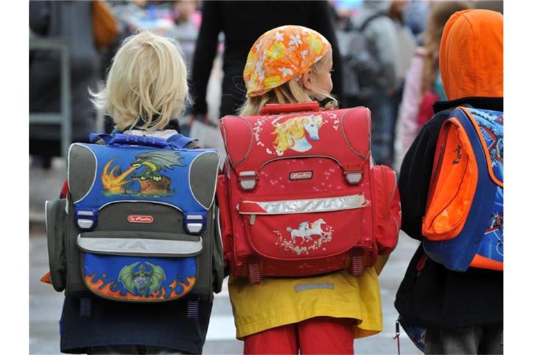 Drei Kinder laufen mit ihren Schulranzen zur Schule. Foto: dpa/Symbolbild