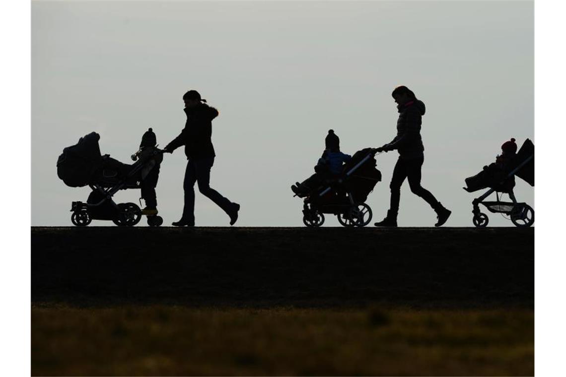 Drei Mütter schieben auf einem Berg ihre Kinderwagen eine Landstraße entlang. Foto: picture alliance / dpa/Symbolbild