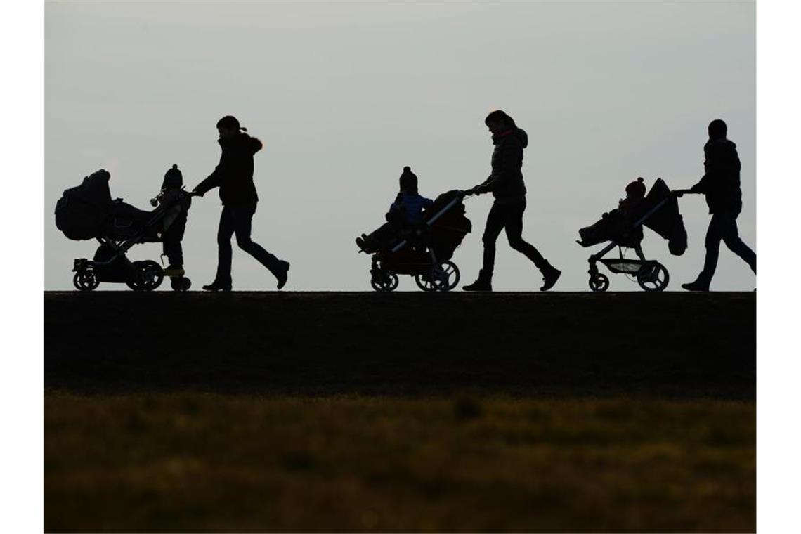 Drei Mütter schieben ihre Kinderwagen eine Landstraße entlang. Ab diesem Montag erhalten die Eltern von rund 18 Millionen Kindern in Deutschland 300 Euro extra. Foto: Felix Kästle/dpa