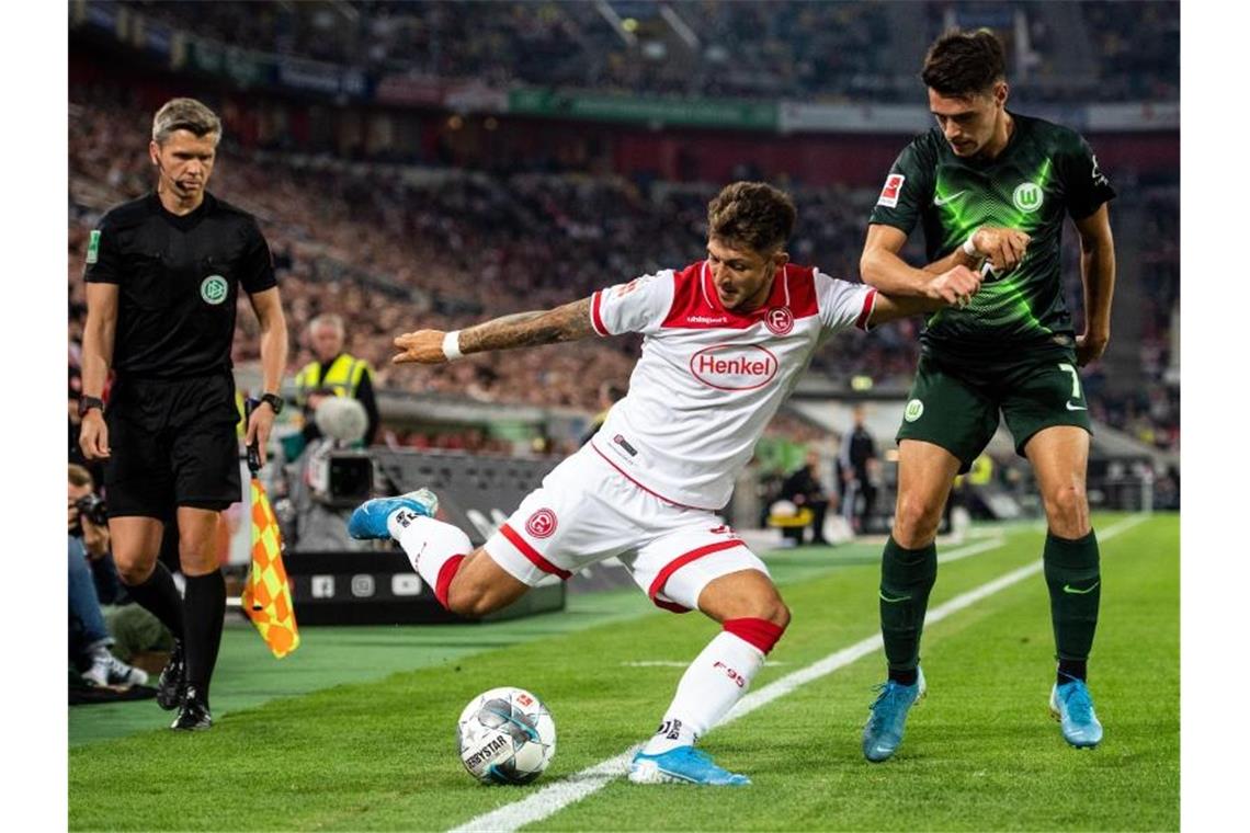 Düsseldorfs Matthias Zimmermann (l) spielt beim Dull mit dem Wolfsburger Josip Brekalo einen Ball im Aus. Foto: Marius Becker