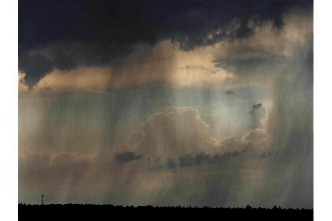 Dunkle Gewitterwolken und Regen sind am Himmel zu sehen. Foto: Nicolas Armer/Archivbild