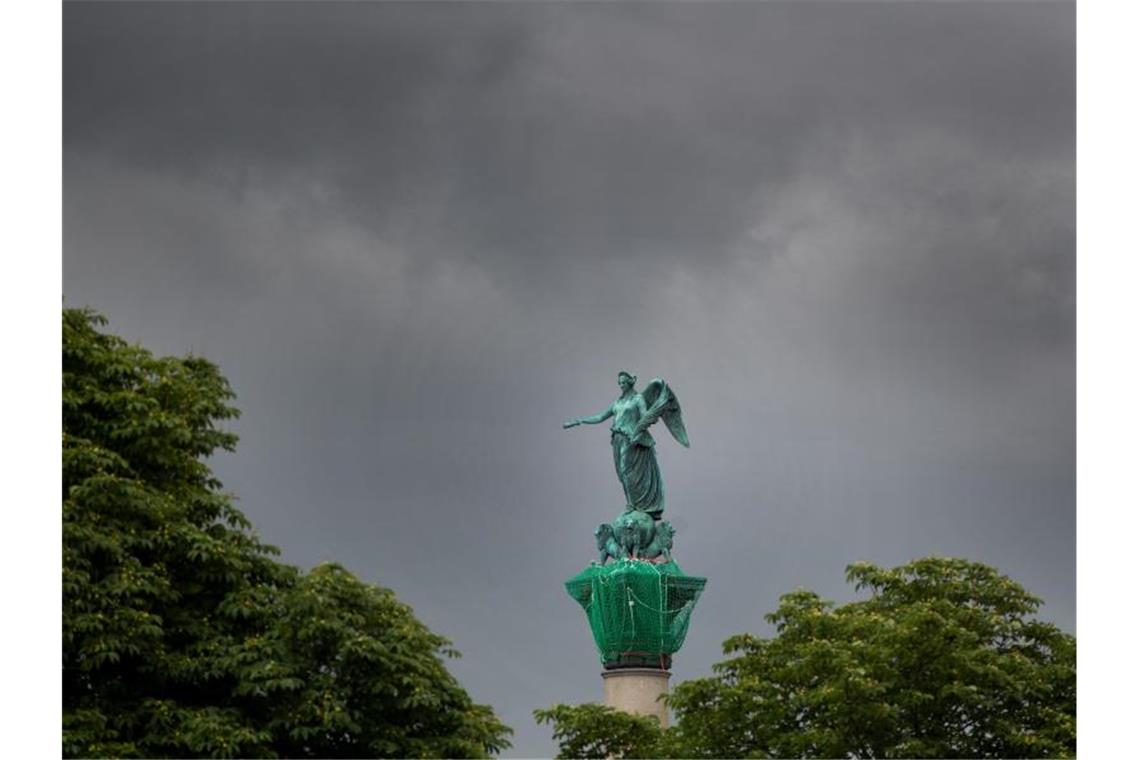 Dunkle Wolken sind am Himmel hinter der Jubiläumssäule auf dem Schlossplatz zu sehen. Foto: Tom Weller/dpa