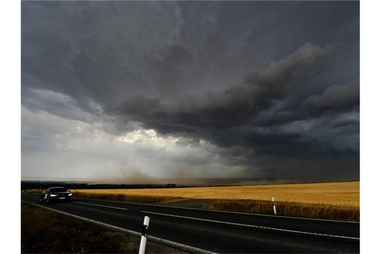 Dunkle Wolken und starker Wind ziehen über ein Feld. Foto: Frank May/Archivbild
