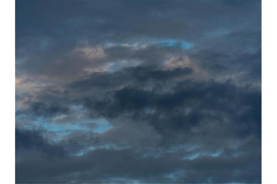 Dunkle Wolken zeichnen sich am Himmel nach Sonnenaufgang ab. Foto: Lino Mirgeler/dpa