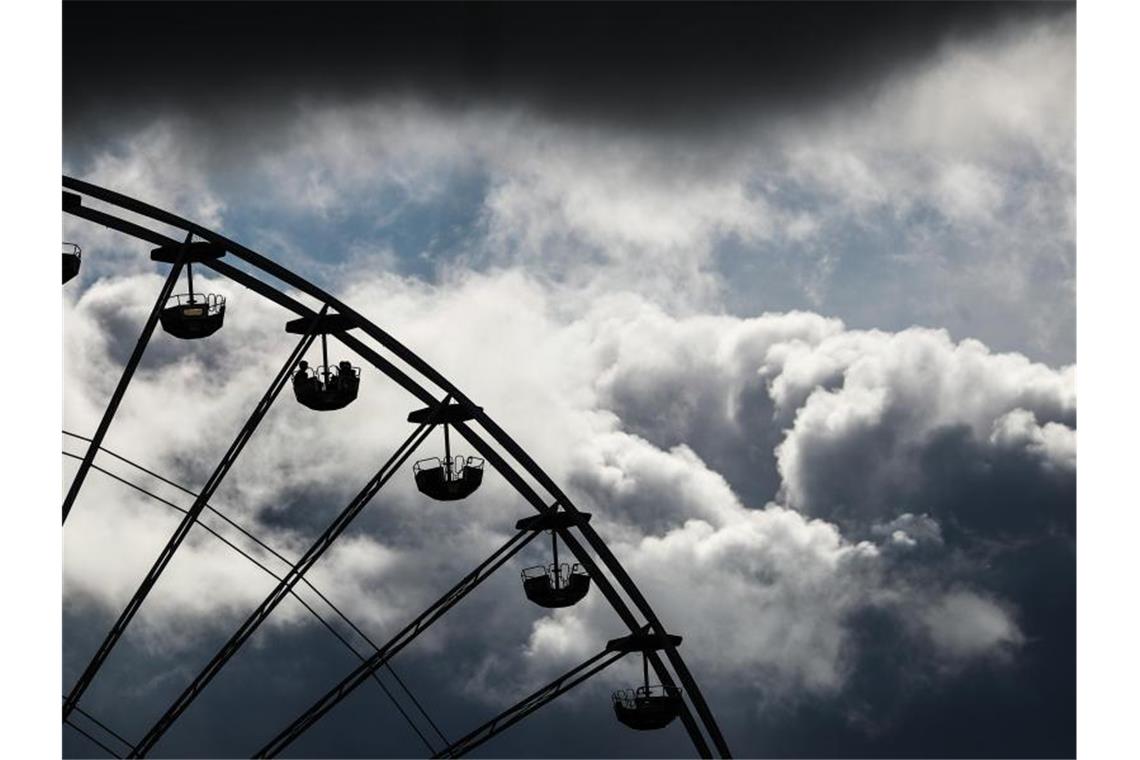Cannstatter Volksfest erneut abgesagt Dunkle Wolken ziehen beim Cannstatter Volksfest hinter einem Riesenrad vorbei. Foto: Christoph Schmidt/dpa/Archivbild