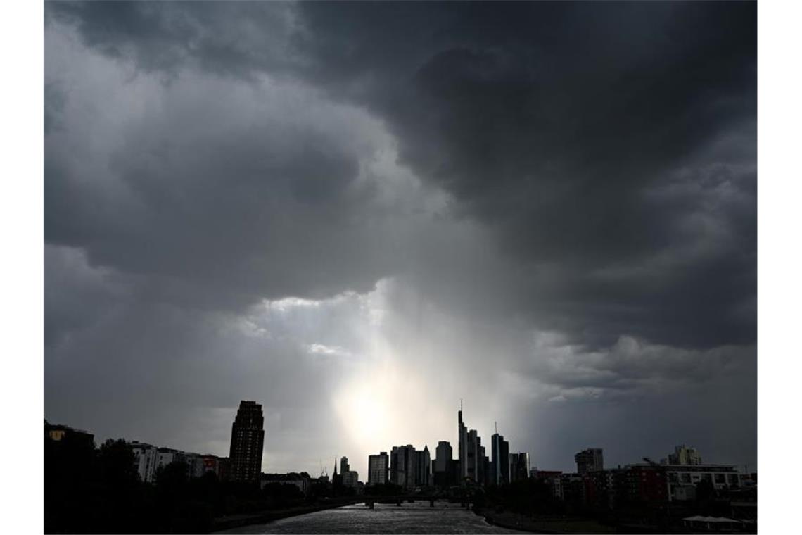 Dunkle Wolken ziehen über die Bankentürme und Hochhäuser während der Regen über der Bankenstadt einsetzt. (Archivbild). Foto: Arne Dedert/dpa