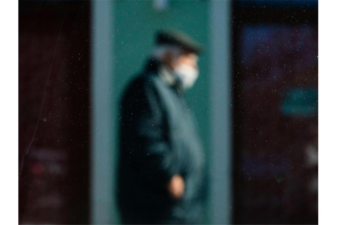 RKI: Sieben-Tage-Inzidenz sinkt auf 60 Durch eine Scheibe fotografiert, ist ein Mann mit Mund-Nasen-Schutz schemenhaft zu erkennen. Foto: Nicolas Armer/dpa/Archivbild