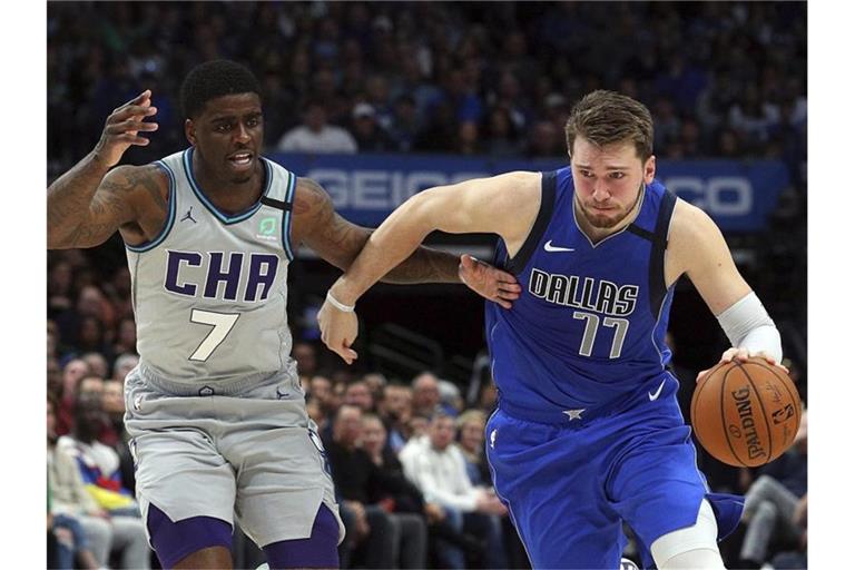 Dwayne Bacon (7/l) von den Charlotte Hornets attackiert Mavs-Spieler Luka Doncic (77). Foto: Richard W. Rodriguez/FR170526 AP/dpa