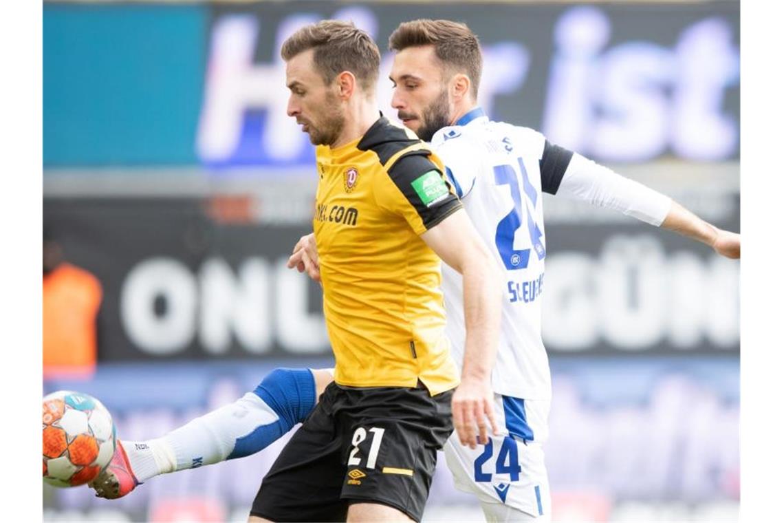 Dynamos Michael Sollbauer (l) wird vom Karlsruher Fabian Schleusener der Ball abgenommen. Foto: Sebastian Kahnert/dpa-Zentralbild/dpa