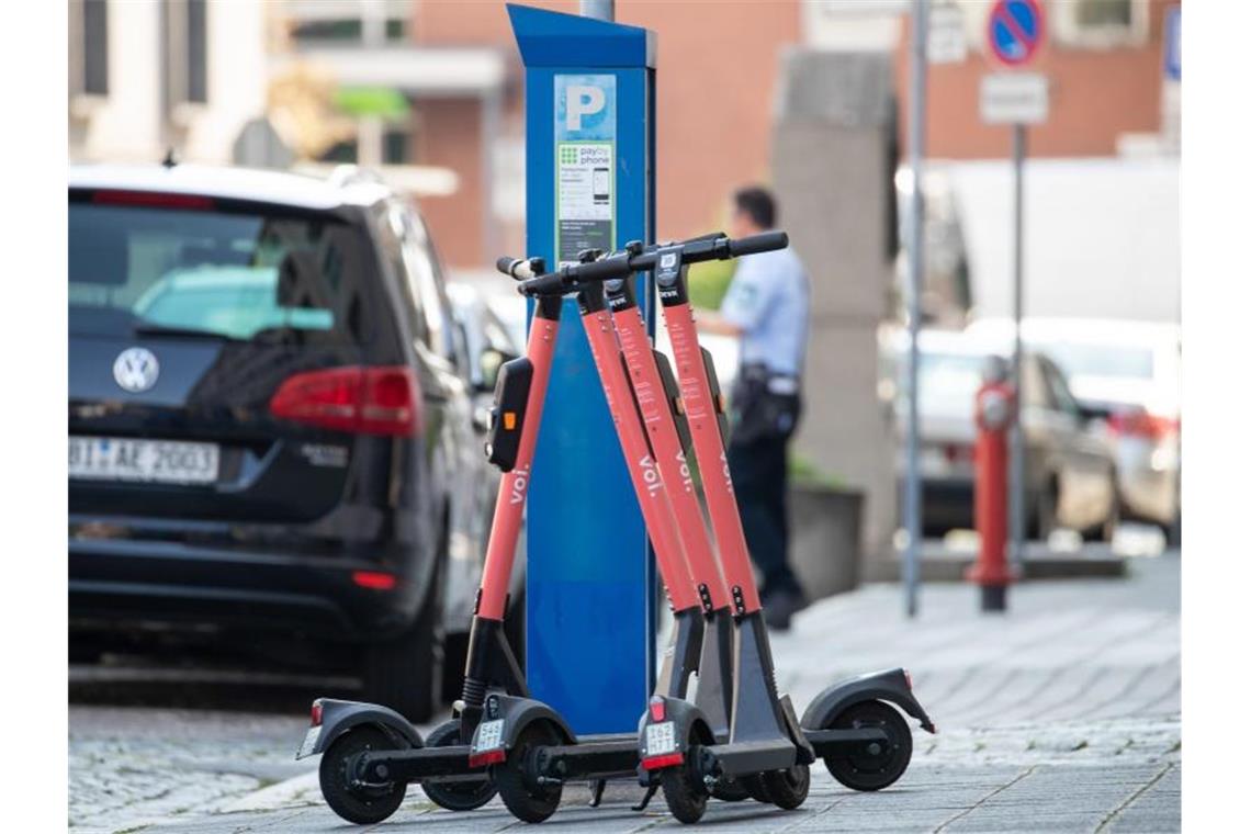 E-Scooter stehen auf dem Bürgersteig neben einem Parkscheinautomat. Foto: Daniel Karmann/dpa