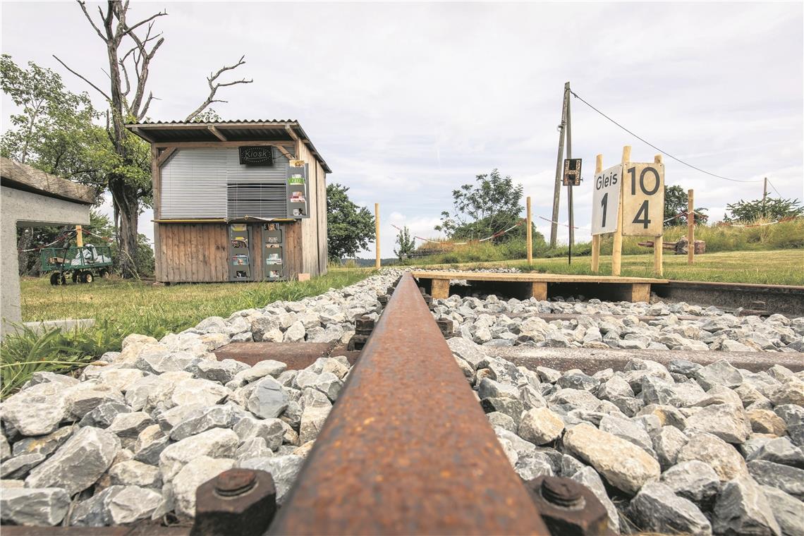 Echte Bahngleise im Schotterbett, eine Schranke und Bahnhofsbeschilderung: Das ist die Kulisse für die Freiluftinszenierung „Abgefahrn!“ auf der Apfelwiese hinter dem Theater.