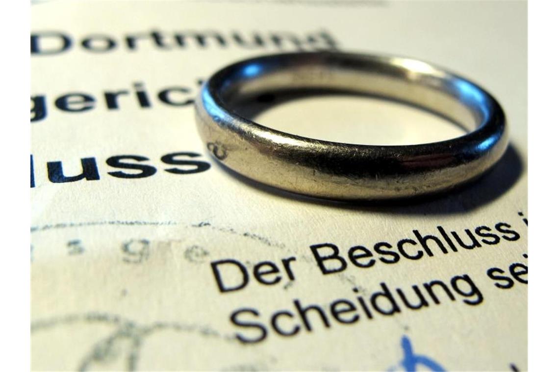 Ehering auf einem Gerichtsbeschluss über eine Scheidung. Rund rund 149 000 Ehen wurden im vergangenen Jahr geschieden. Foto: Franz-Peter Tschauner/dpa