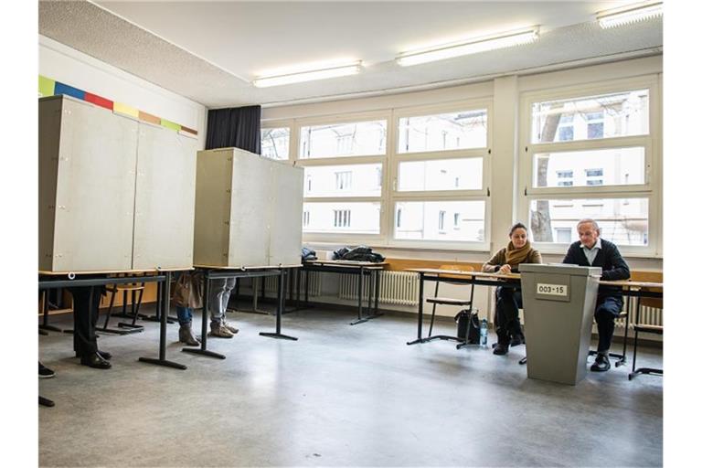 Ehrenamtliche Wahlhelfer sitzen in einem Wahllokal vor einer Urne. Foto: Wolfram Kastl/dpa/Archivbild