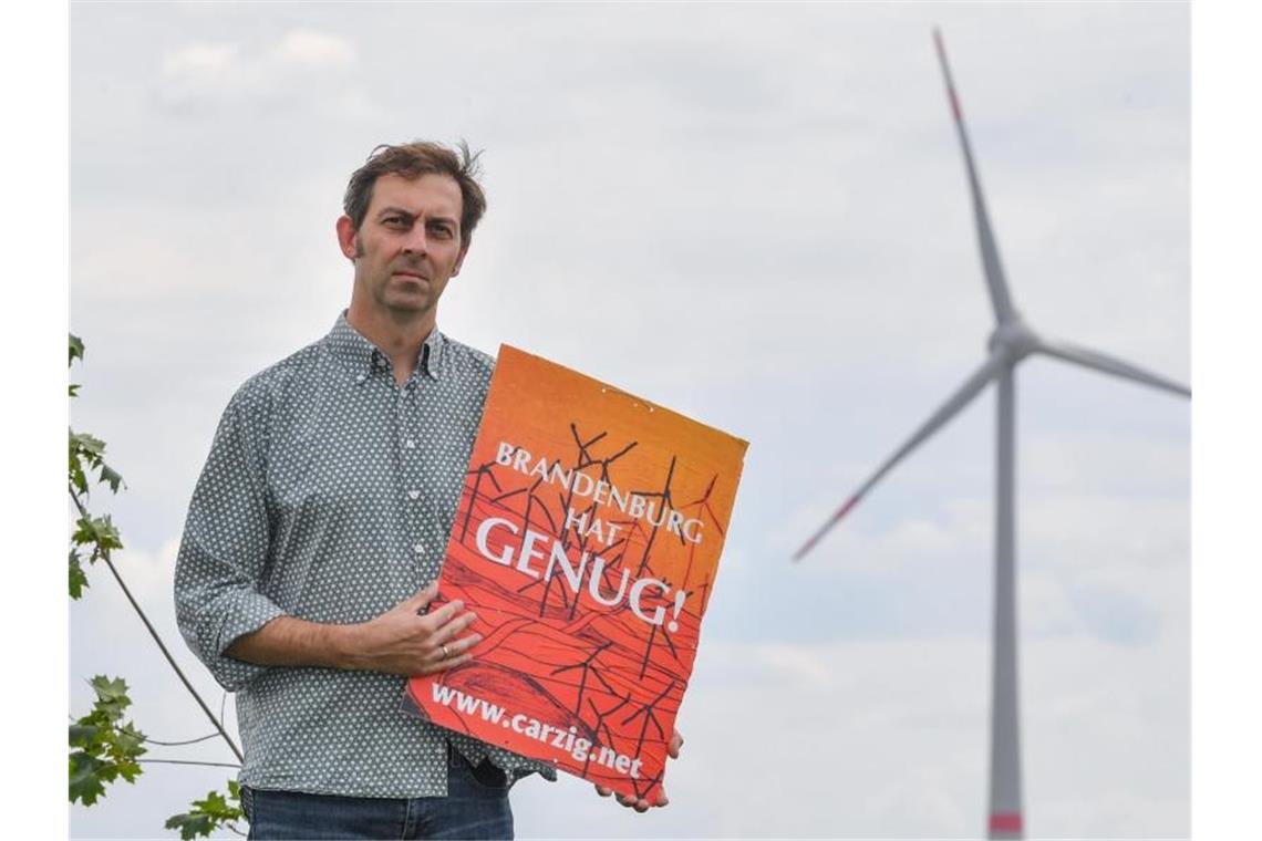 Eigenheimbesitzer Stefan Hellert auf seinem Grundstück. In rund 1500 Metern Entfernung dreht sich der Rotor einer Windenergieanlage. Foto: Patrick Pleul/zb/dpa