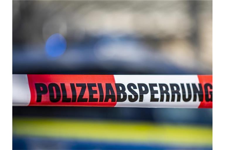 Ein Absperrband mit der Aufschrift „Polizeiabsperrung“ ist vor einem Polizeiwagen aufgespannt. Foto: David Inderlied/dpa/Symbolbild