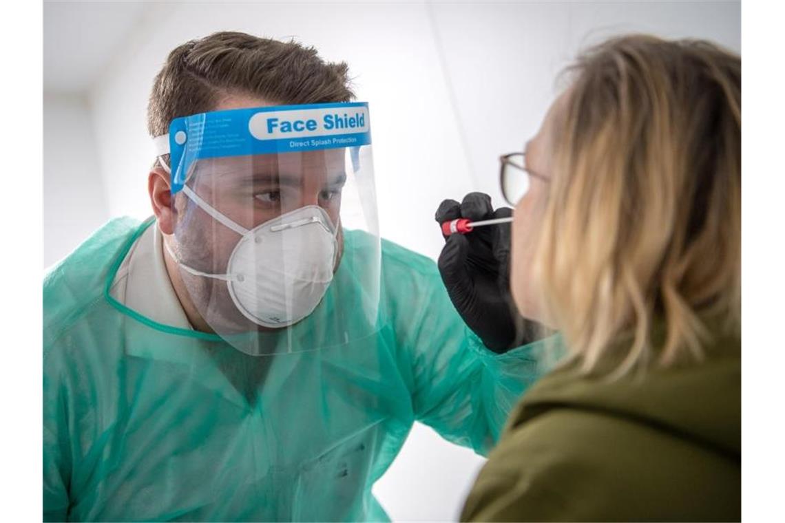 Ein Abstrich für einen PCR-Test wird von einem Mitarbeiter im Corona-Testzentrum genommen. Foto: Sina Schuldt/dpa