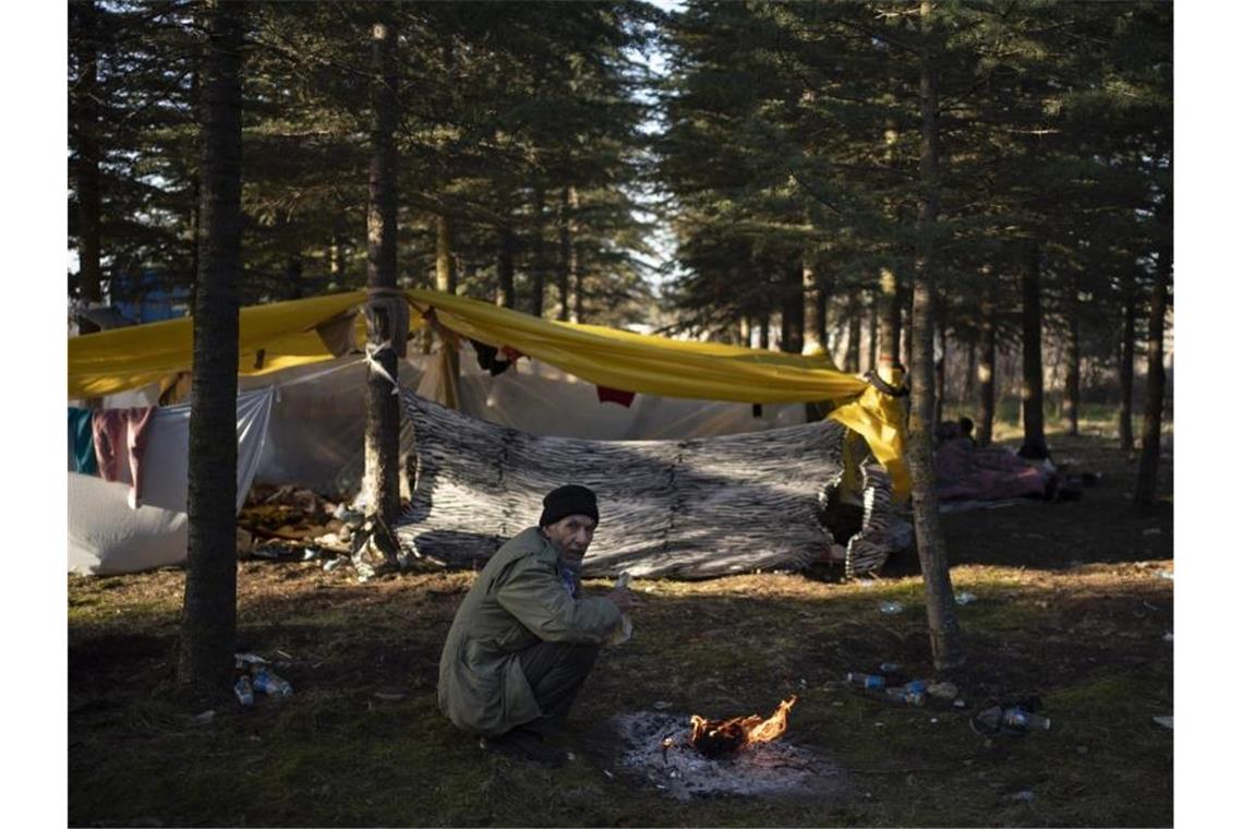 Küstenwachen geraten in Ägäis aneinander Ein älterer Mann wärmt sich an einem Lagerfeuer. Foto: Felipe Dana/AP/dpa