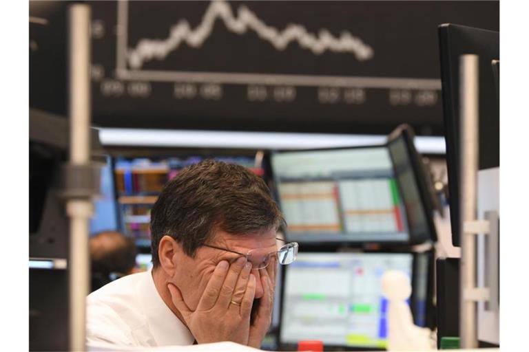 Ein Aktienhändler reibt sich auf dem Parkett der Frankfurter Börse die Augen. Foto: Arne Dedert/dpa