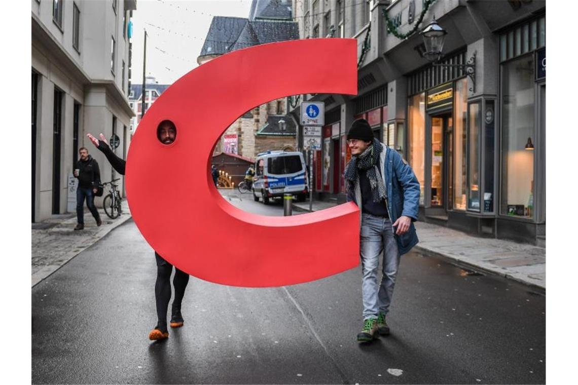 Ein Aktivist geht mit einem nachgebauten Buchstaben C aus dem Logo der CDU vor der Nikolaikirche in Leipzig über eine Straße. Foto: Hendrik Schmidt/dpa